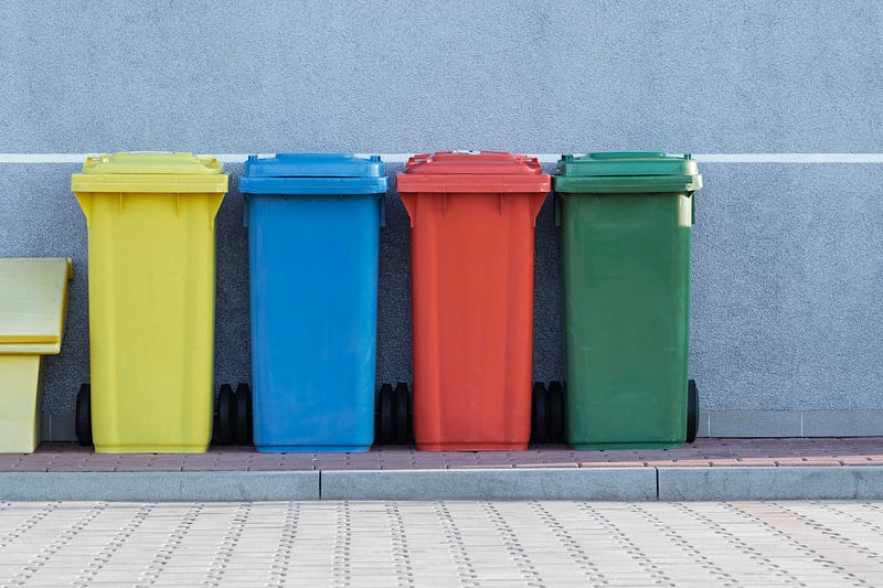 Four garbage bins in a street.